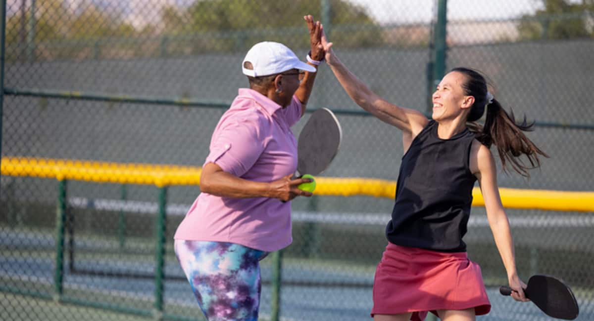 2 women pickleball players high 5
